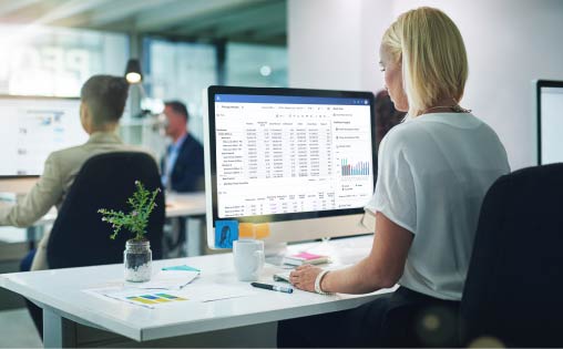 一个女人在她的办公桌上用电脑处理电子表格。